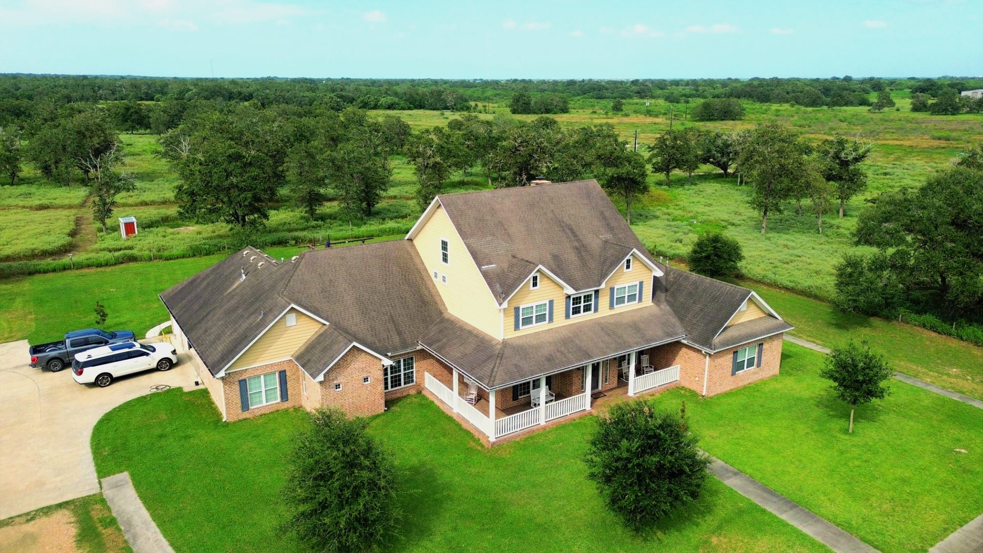 Aerial front view of a two-story country farmhouse with wraparound porch