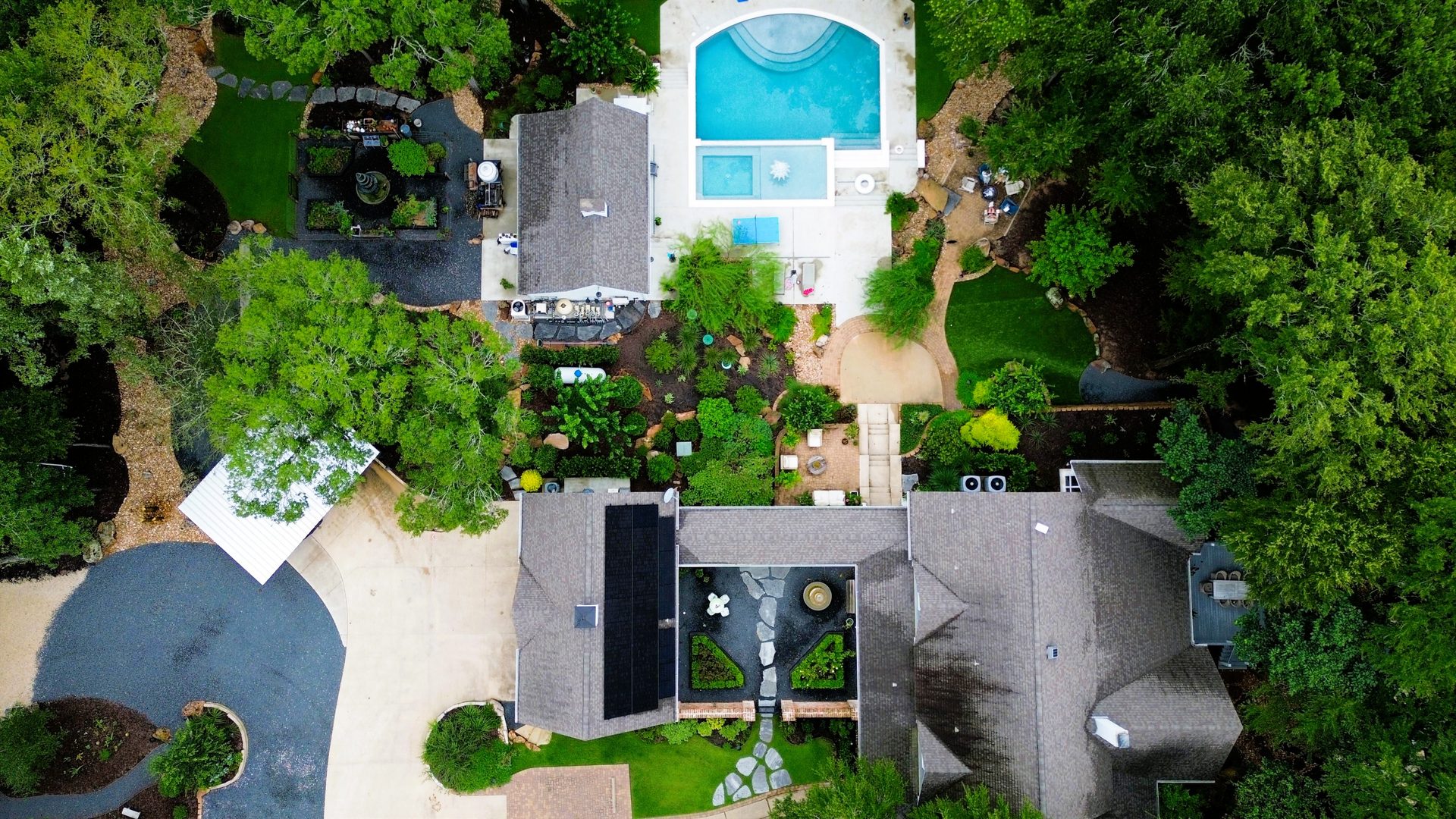 Top-down aerial of an estate home with pool, gardens, and solar array