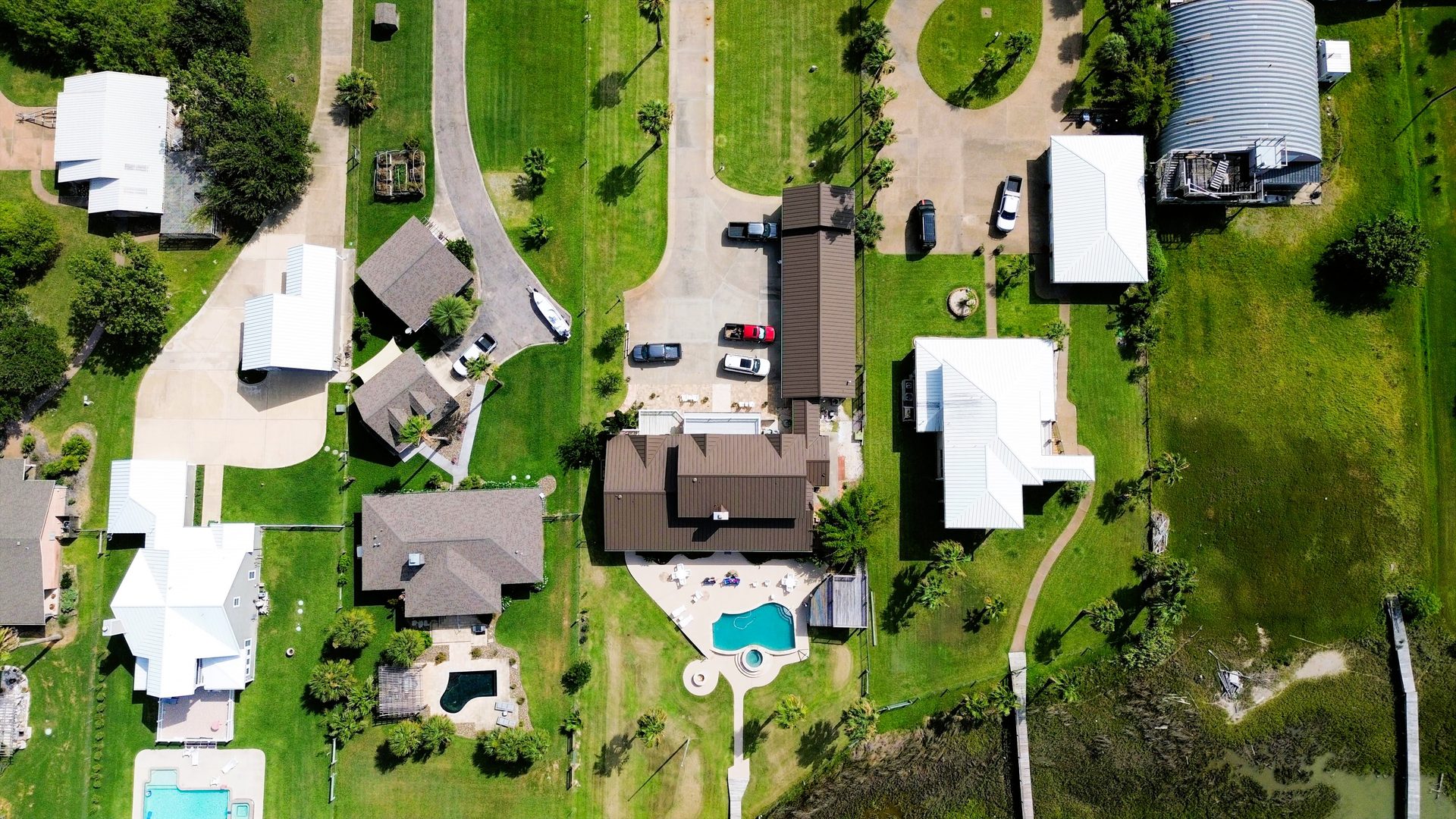 Top-down aerial of a coastal neighborhood with pools