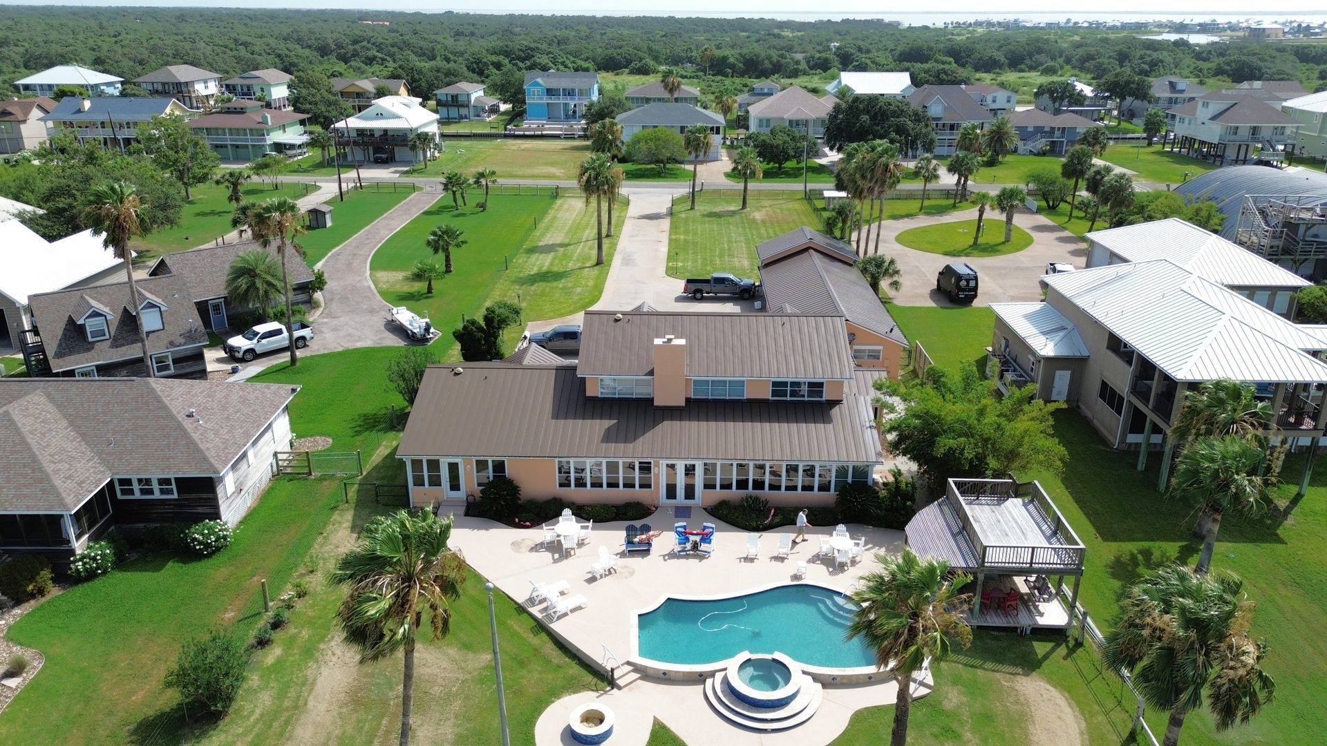Wide aerial of a coastal home and surrounding neighborhood